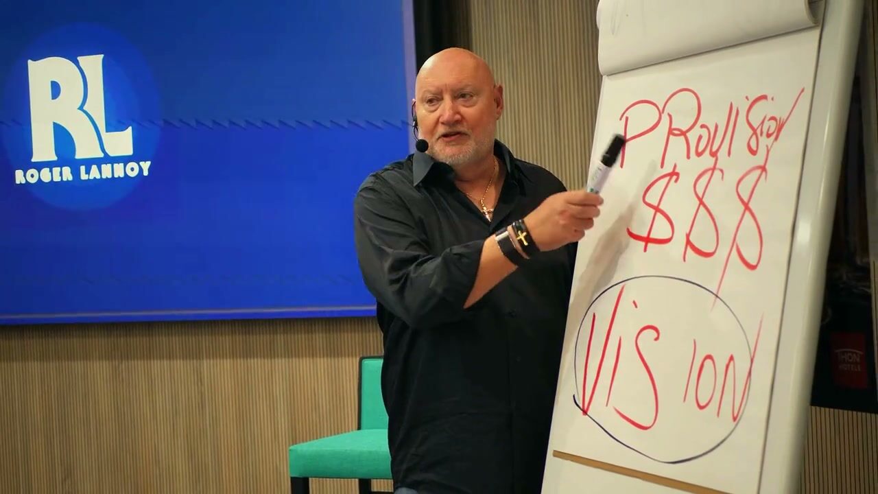 Roger Lannoy devant un tableau où est écrit le mot vision