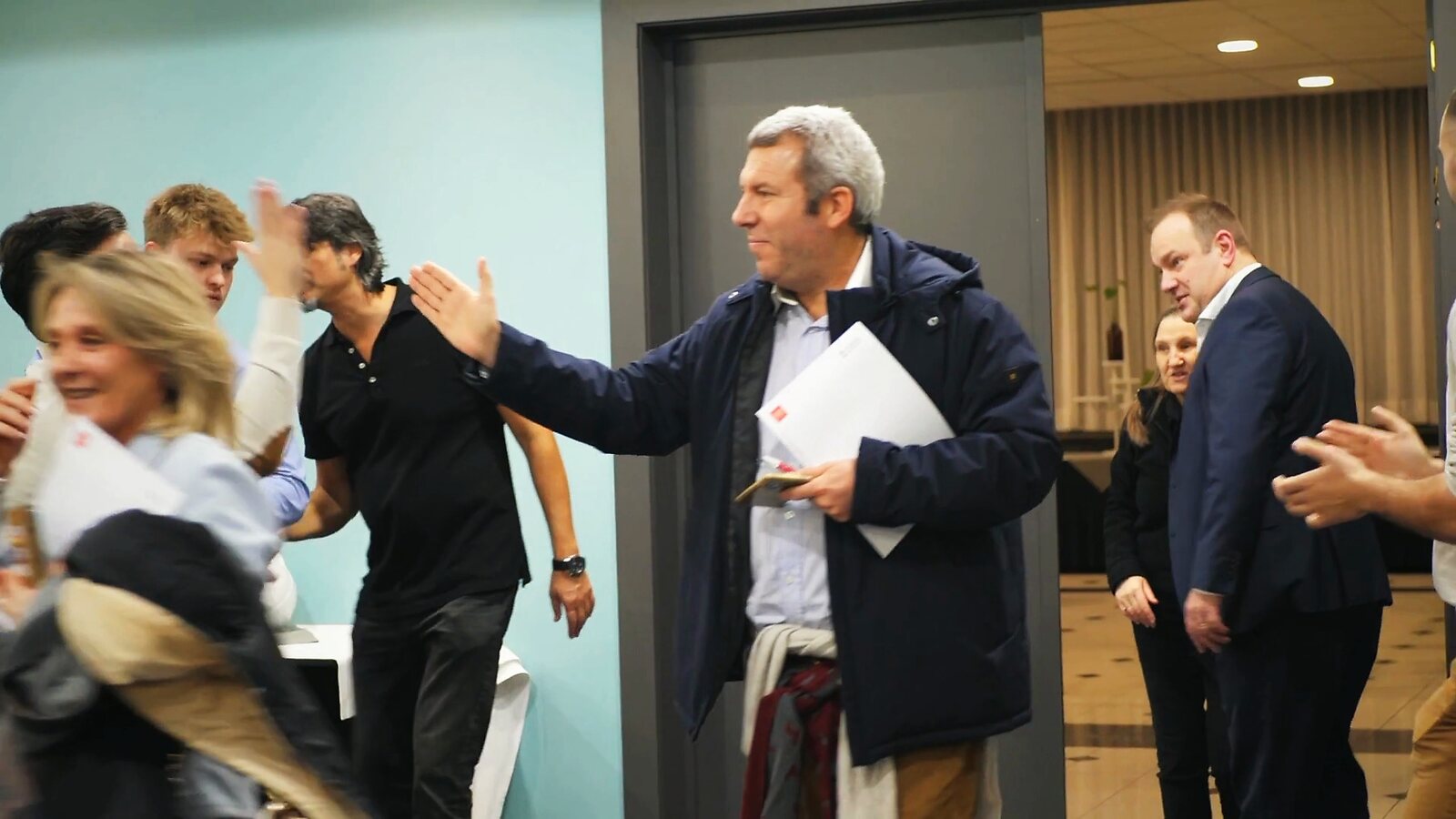 Participants qui se saluent avec énergie pendant un séminaire de Roger Lannoy