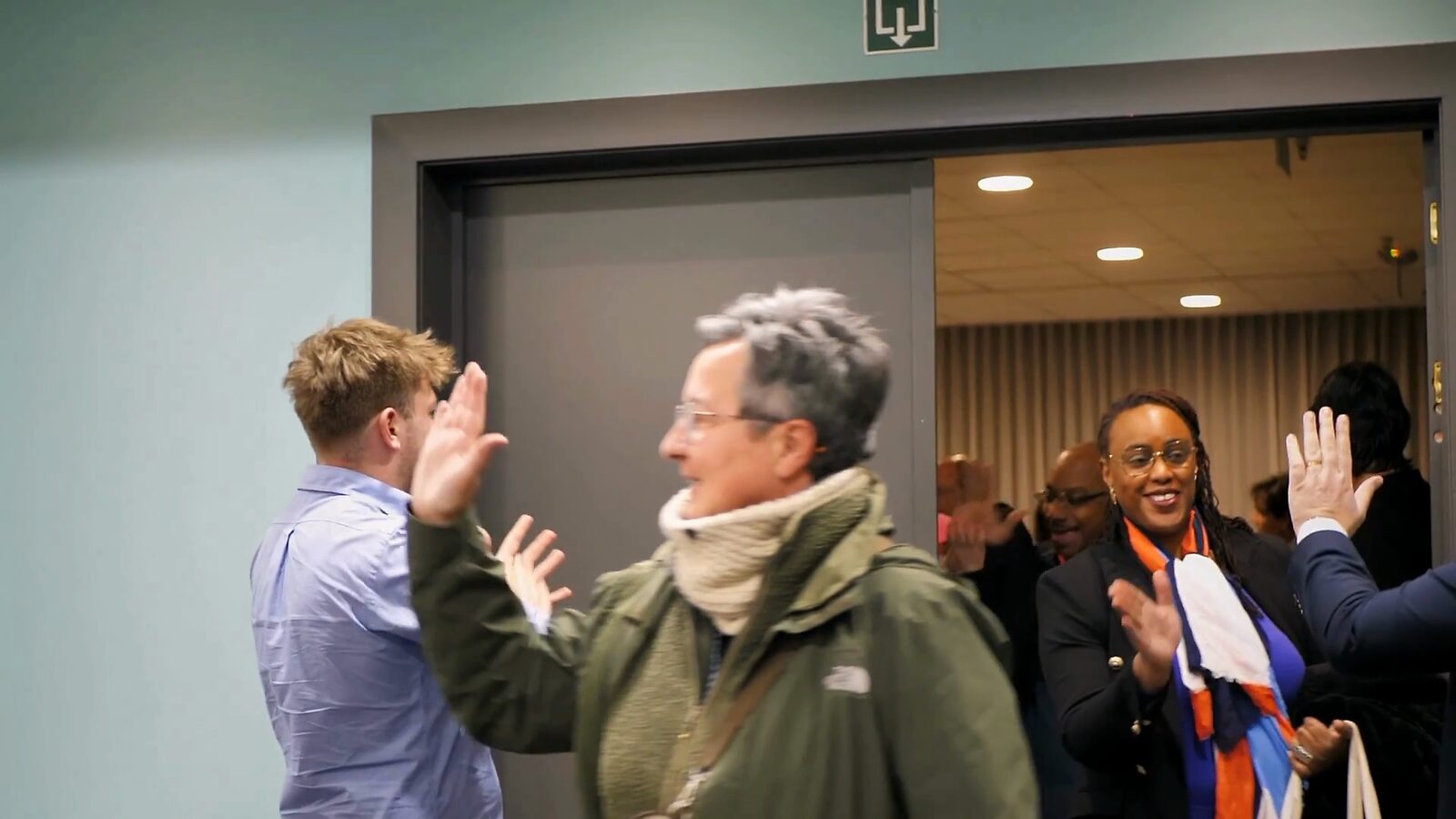 Participants qui se saluent avec enthousiasme à l’entrée de la salle